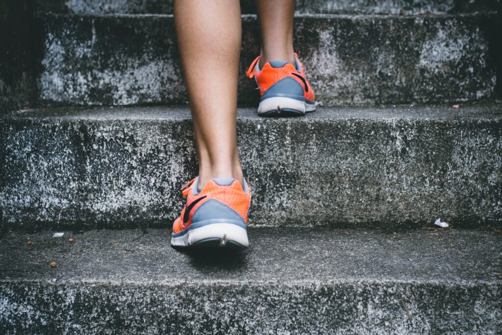 Ein Mensch in Sportschuhen geht eine Steintreppe hinauf