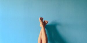 Weibliche Beine, im Liegen hochgestreckt und an eine blaue Wand gelehnt
