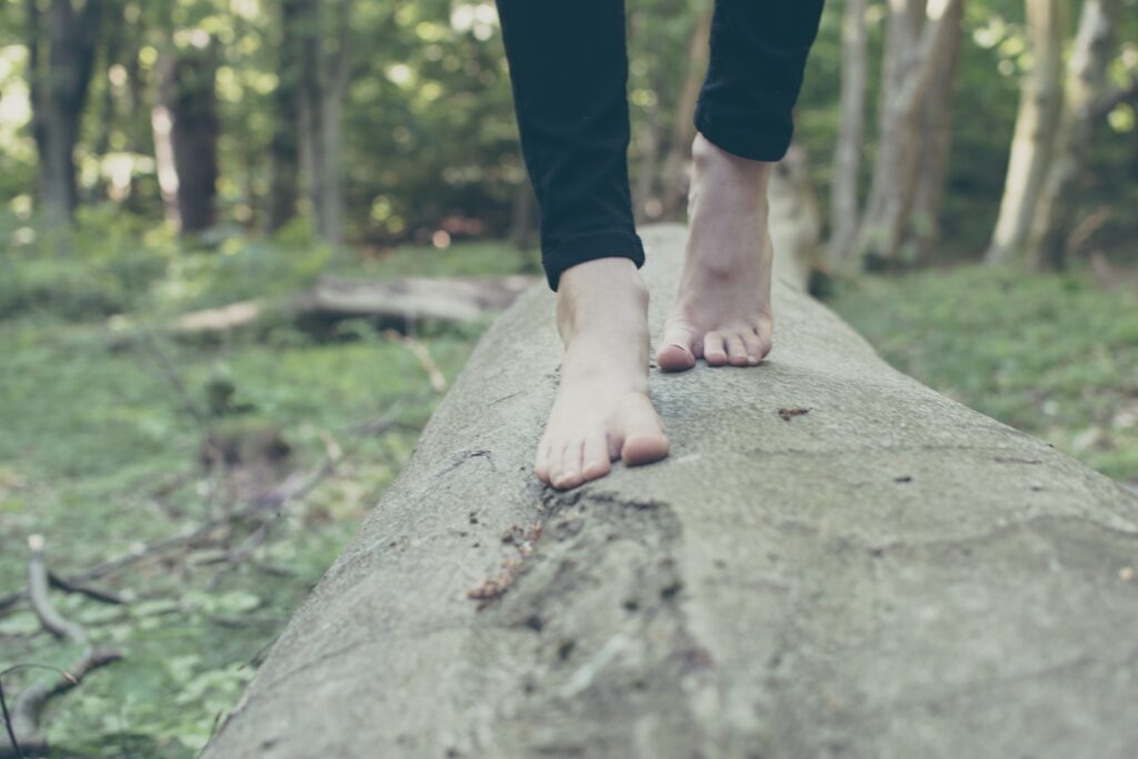 Eine Frau balanciert auf einem Holzstamm im Wald