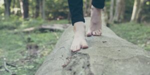 Eine Frau balanciert auf einem Holzstamm im Wald