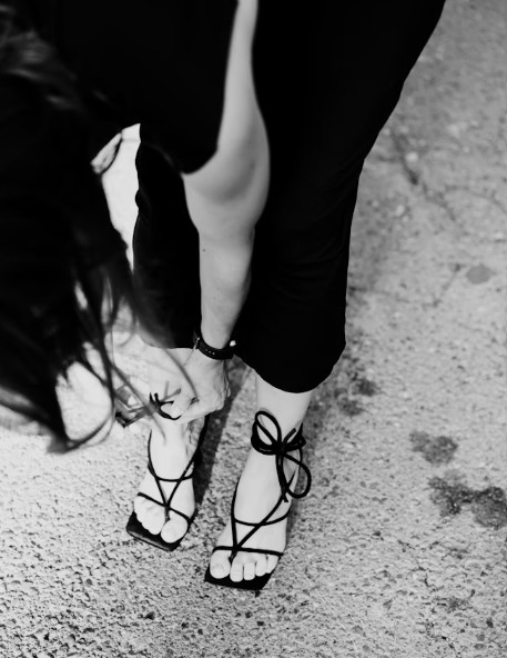 Eine Frau in High Heels beugt sich vor, schwarz und weiß.